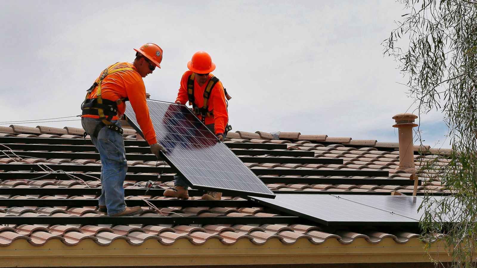 Electricians install solar panels on a roof for Arizona Public Service company in Goodyear, Ariz. (Photo by Matt York, Associated Press)